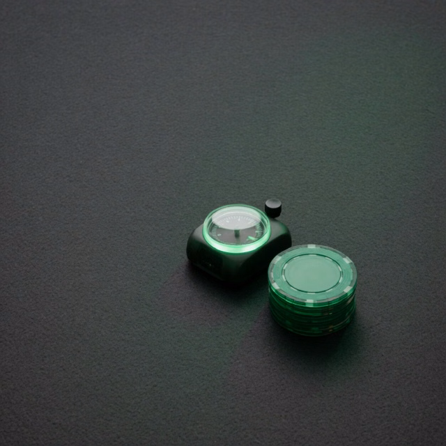 Hand setting a timer beside a small stack of chips on a calm green surface